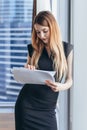 Woman holding documents, looking through papers, studying the report standing near window with view on skyscrapers Royalty Free Stock Photo