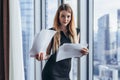 Woman holding documents, looking through papers, studying the report standing near window with view on skyscrapers Royalty Free Stock Photo