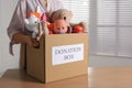 Woman holding donation box with child goods indoors, closeup. Space for text Royalty Free Stock Photo