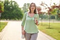 Woman holding drink walking in park Royalty Free Stock Photo