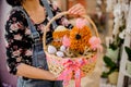 Woman holding an Easter gift consisting of wicker basket with chicken and egg shape flowers Royalty Free Stock Photo