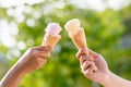 woman holding and eating ice cream in the park. Hands holding melting ice cream waffle cone in hand on summer nature light backgr Royalty Free Stock Photo