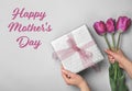 Woman holding elegant gift box and tulips for Mother`s Day on light background Royalty Free Stock Photo