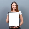 Woman holding empty frame with space for your advertisement against gray background Royalty Free Stock Photo