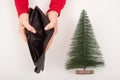 A woman is holding an empty purse next to a small artificial Christmas tree. The financial crisis during the holidays Royalty Free Stock Photo