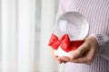 Woman holding empty snow globe with red bow, closeup. Space for text Royalty Free Stock Photo