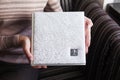 Woman holding a family photobook. White photo album in female hands. Wedding or family photoalbum with cover of genuine leather.