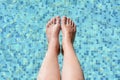 Woman holding feet over water in swimming pool, closeup Royalty Free Stock Photo