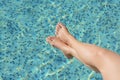 Woman holding feet over water in swimming pool, closeup Royalty Free Stock Photo