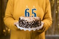 Woman holding a festive cake with number 65 candles while celebrating birthday party. Birthday holiday party people Royalty Free Stock Photo