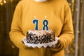 Woman holding a festive cake with number 78 candles while celebrating birthday party. Birthday holiday party people