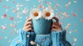Woman holding flower-adorned mug, spring petals, blue backdrop Royalty Free Stock Photo