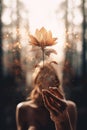 A woman holding a flower in front of her face. Generative AI image. Royalty Free Stock Photo