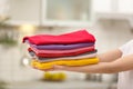 Woman holding folded clean clothes indoors, closeup.