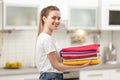 Woman holding folded clean clothes in kitchen
