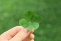 Woman holding four-leaf clover outdoors