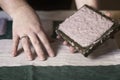 A woman holding a frame for making paper sheets from recycled paper. Selective focus. Household hobby, paper recycling