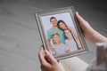 Woman holding framed family photo indoors