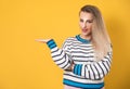 Woman holding free advertising space for your product on his palm, isolated on yellow background. Happy promoter girl