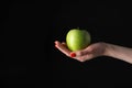 Woman holding fresh ripe green apple against black background, closeup Royalty Free Stock Photo