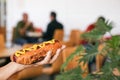 Woman holding fresh tasty hot dog with mustard in cafe, closeup. Space for text Royalty Free Stock Photo