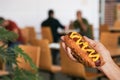 Woman holding fresh tasty hot dog with mustard in cafe, closeup. Space for text Royalty Free Stock Photo