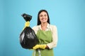 Woman holding full garbage bag on blue background Royalty Free Stock Photo