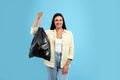 Woman holding full garbage bag on blue background Royalty Free Stock Photo