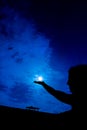 Woman holding full moon in hand against night sky