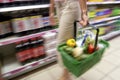 Woman Holding Full Shopping Basket Along Soda Aisle in Supermarket Royalty Free Stock Photo