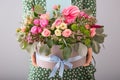 Woman holding gift box with beautiful flowers on light background Royalty Free Stock Photo