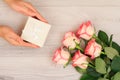 Woman holding a gift box in the hands with flowers on the background Royalty Free Stock Photo