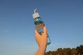 Woman holding glass bottle with water against blue sky, closeup Royalty Free Stock Photo