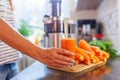 Woman holding glass of carrot juice with fresh carrots on kitchen counter Royalty Free Stock Photo