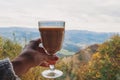 Woman holding a glass with chai latte with a view to mountains