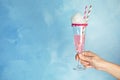 Woman holding glass with cocktail and candy cotton on color background, closeup. Royalty Free Stock Photo