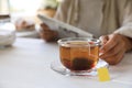 Woman holding glass cup with tea bag at white wooden table, closeup. Space for text Royalty Free Stock Photo