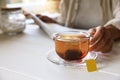 Woman holding glass cup with tea bag at white wooden table, closeup. Space for text Royalty Free Stock Photo