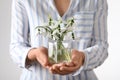 Woman holding glass jar with snowdrops on light background, closeup Royalty Free Stock Photo