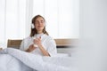 Woman holding glass of milk and listening relax song at music application in the morning on the bed