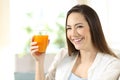 Woman holding a glass of orange juice looking at you Royalty Free Stock Photo