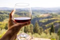 Woman holding a glass of red wine with beautiful landscape of Italy in a background on a sunny day. Royalty Free Stock Photo