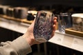 Woman holding glass from a shelf in homeware store.