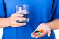 Woman holding glass of water and pack of pills