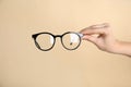 Woman holding glasses on beige background, closeup. Ophthalmologist prescription