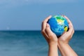 Woman holding globe of the Earth on a background of the sea.
