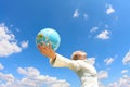 Woman holding a globe under sky