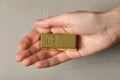 Woman holding gold bar against grey textured background, closeup Royalty Free Stock Photo