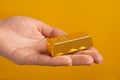 Woman holding gold bar on orange background Royalty Free Stock Photo