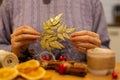 Woman holding gold festive, christmas, leaf ornament, diy decorations, blurry foreground, purple cable knit sweater in the